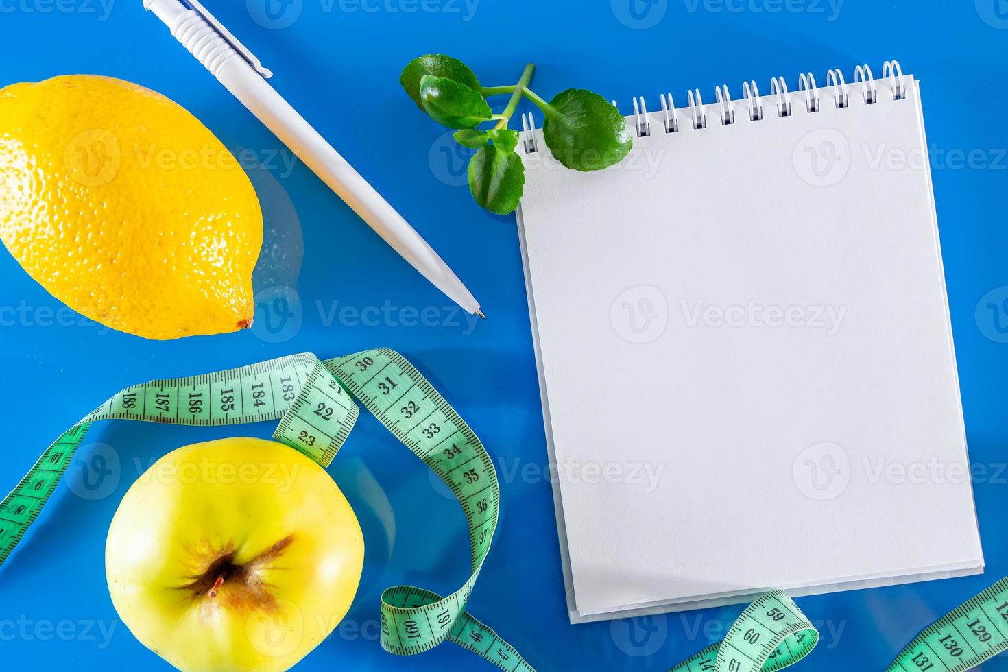 blanco notebook, fruit en meetlint op een blauwe achtergrond foto