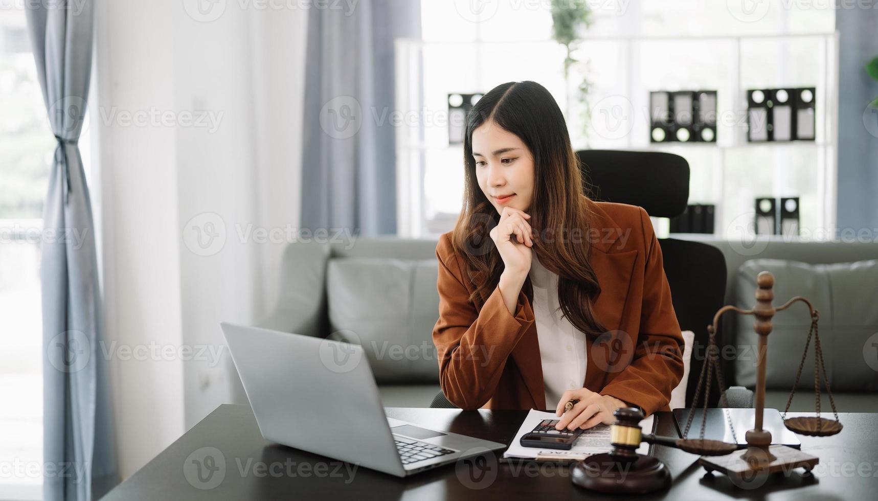 Aziatisch vrouw advocaat chatten online met cliënt Aan laptop, smartphone bespreken details van rechtszaak. in modern kantoor foto