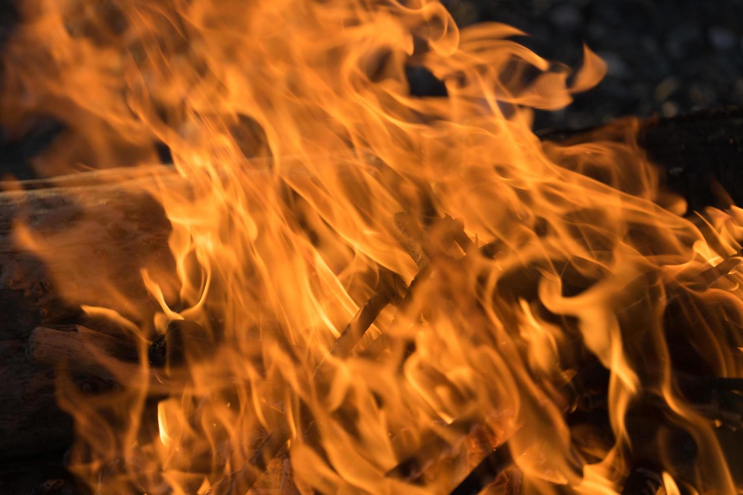 heldere vlam van vuur bij de brandende houtblokken op de rotsachtige kust foto