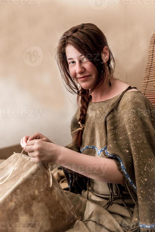 jong lakota-meisje zit in een tipi en maakt een doos van ongelooide huid foto