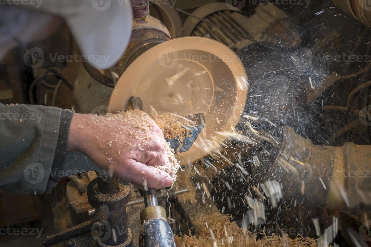 een houten kom maken op een draaibank in een oude kleine werkplaats foto