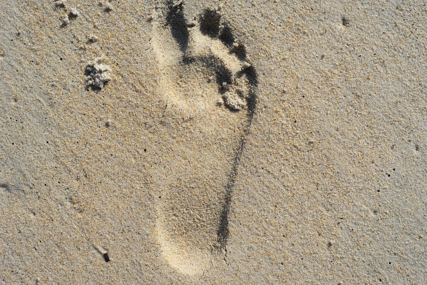 natuurlijke achtergrond van zand met de afdruk van een menselijke voet. foto
