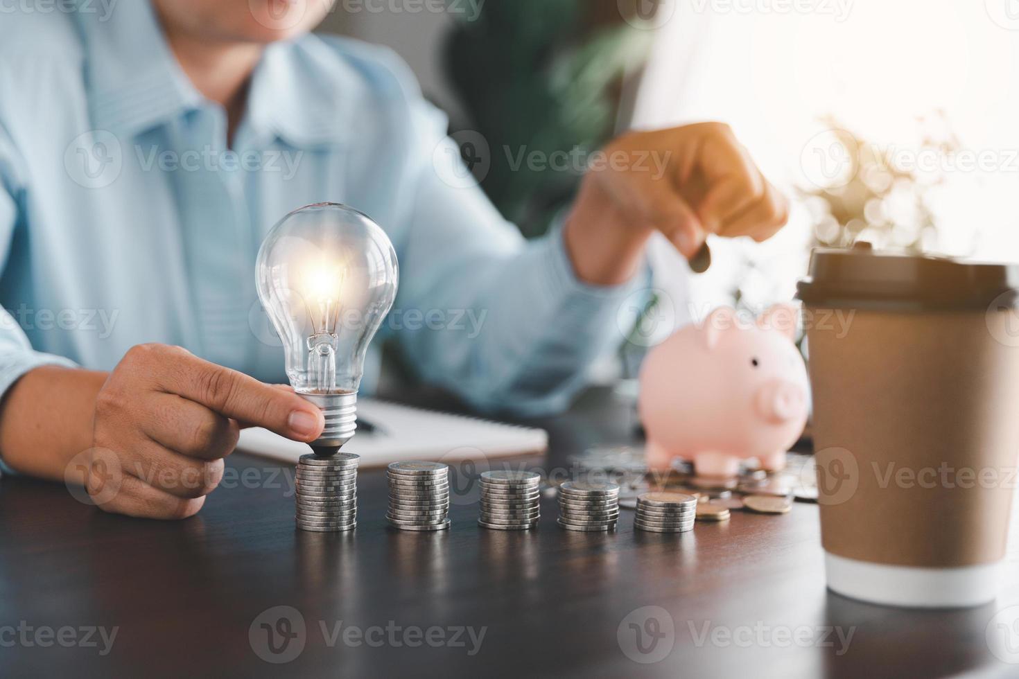 zakenvrouw hand- Holding gloeilamp en zetten munt in varkentje bank. idee van besparing energie en accounting financiën in huis en familie, opslaan wereld en energie stroom. opslaan energie plan concept foto