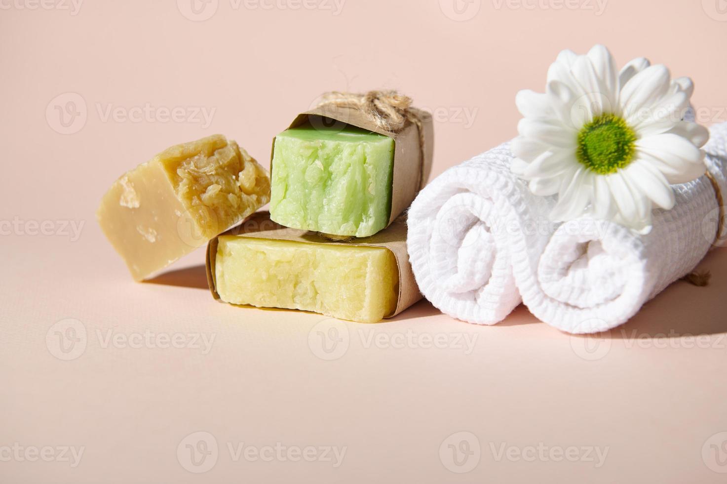 wit handdoek, kamille bloem en stack van biologisch zeep bars met natuurlijk ingrediënten, geïsoleerd Aan beige. spa concept foto