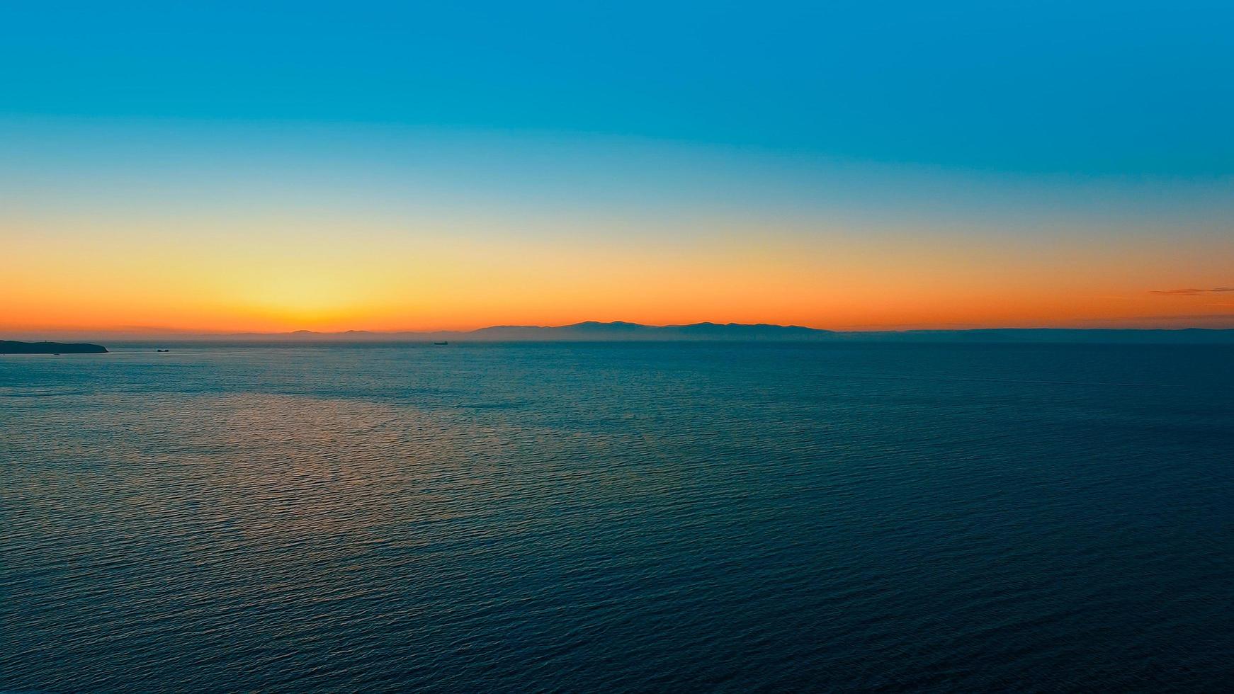 zeegezicht met oranje zonsondergang over de horizon. foto