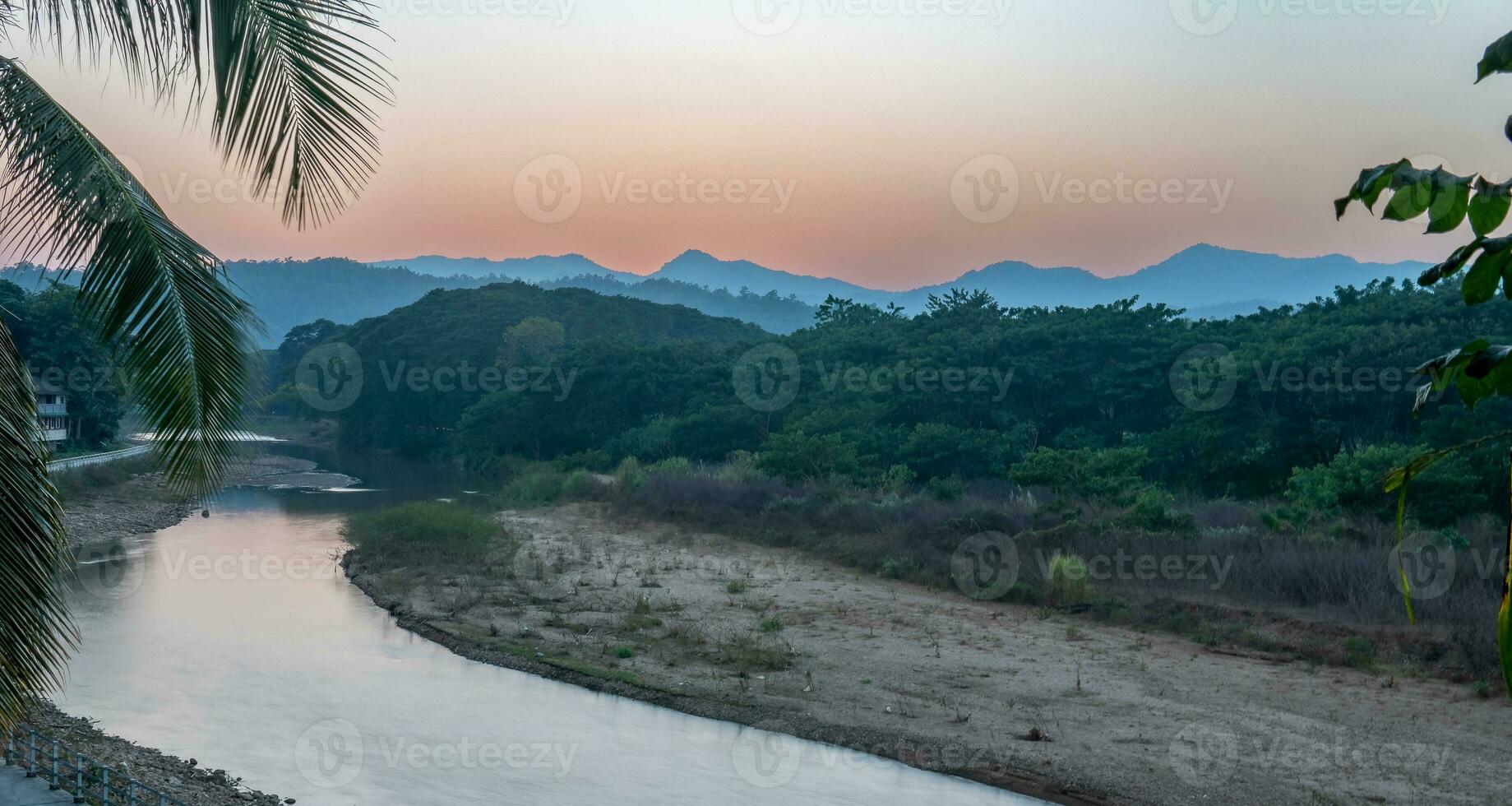 zonsondergang over de bergen met rivier en palmboom foto