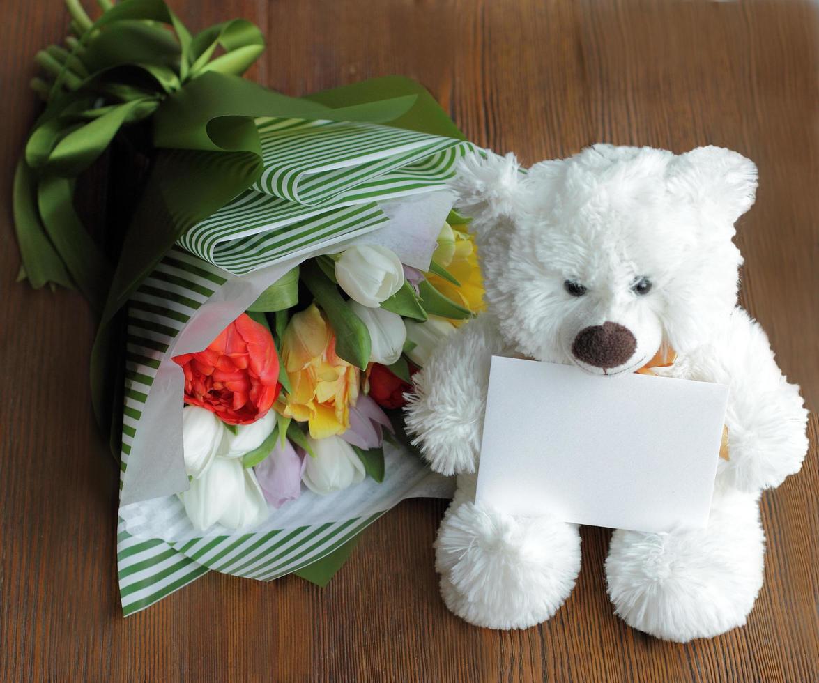 witte teddybeer met lege notecard en boeket foto