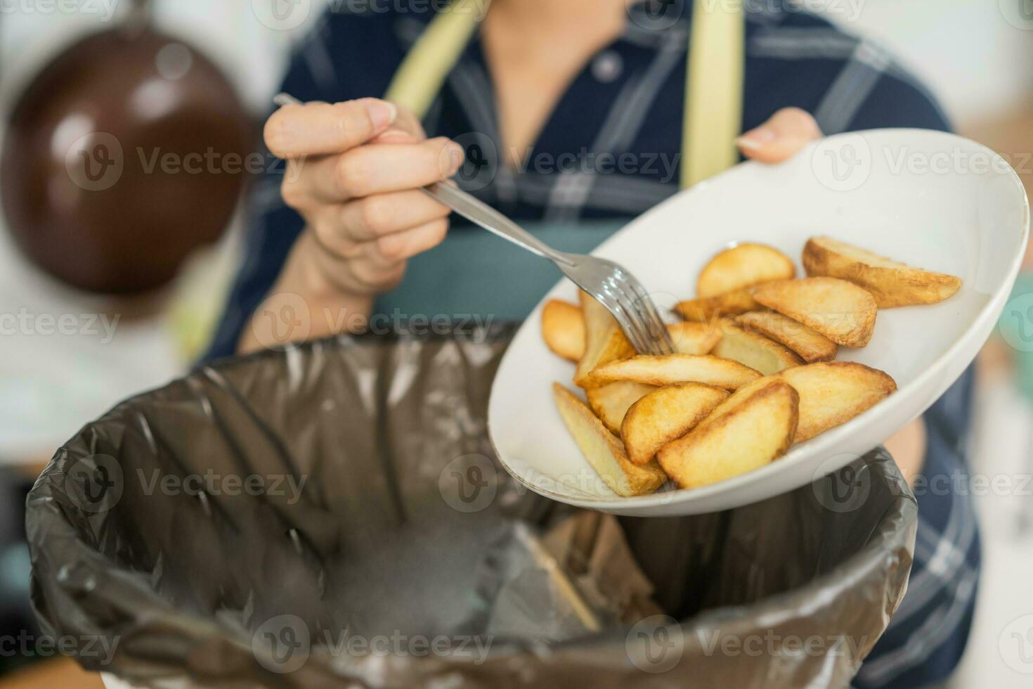cholesterol van rommel maaltijd is dik maaltijd, hand- van Aziatisch jong huishouden vrouw schrapen, het werpen voedsel restjes in afval, uitschot bak van aardappel chip, tussendoortje. milieuvriendelijk aansprakelijk, ecologie foto