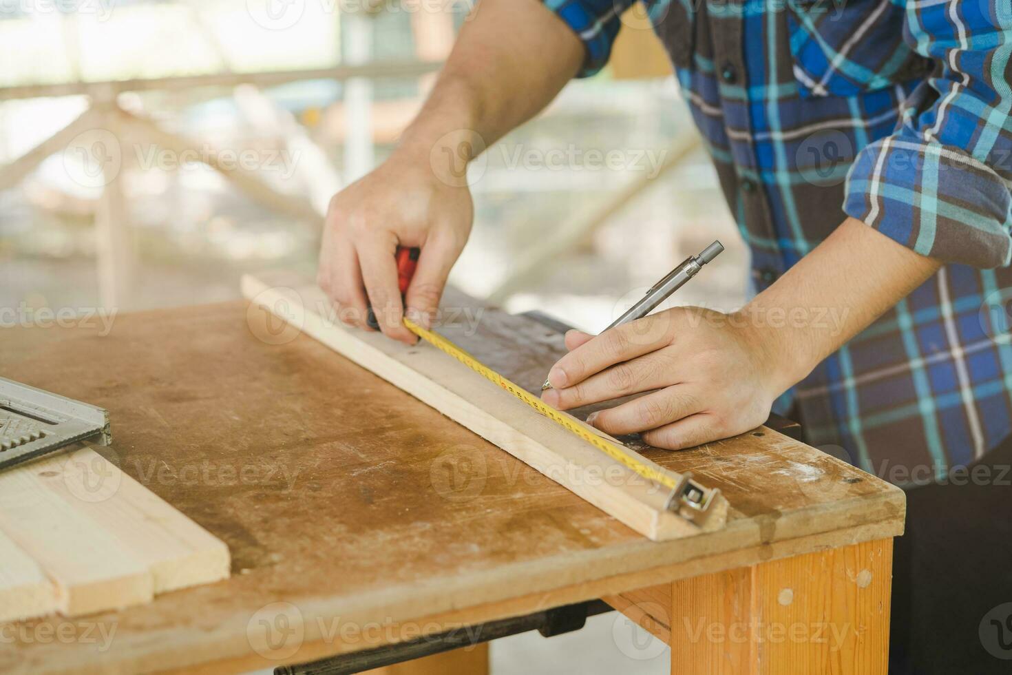 timmerwerk professioneel, hand- van Aziatisch jong Mens, mannetje timmerman gebruik plakband meeteenheid, gereedschap Aan bord hout in klein winkel. houtwerk, meubilair maken, bouw industrie. eigenaar klein bedrijf mensen. foto