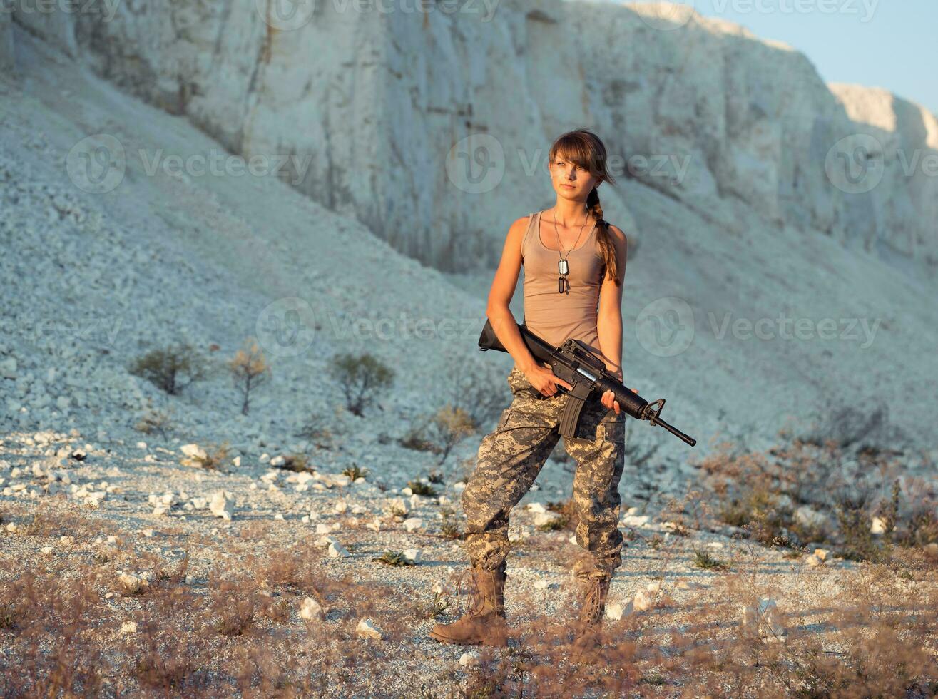 jong vrouw soldaat gekleed in een camouflage met een geweer in de plaats foto