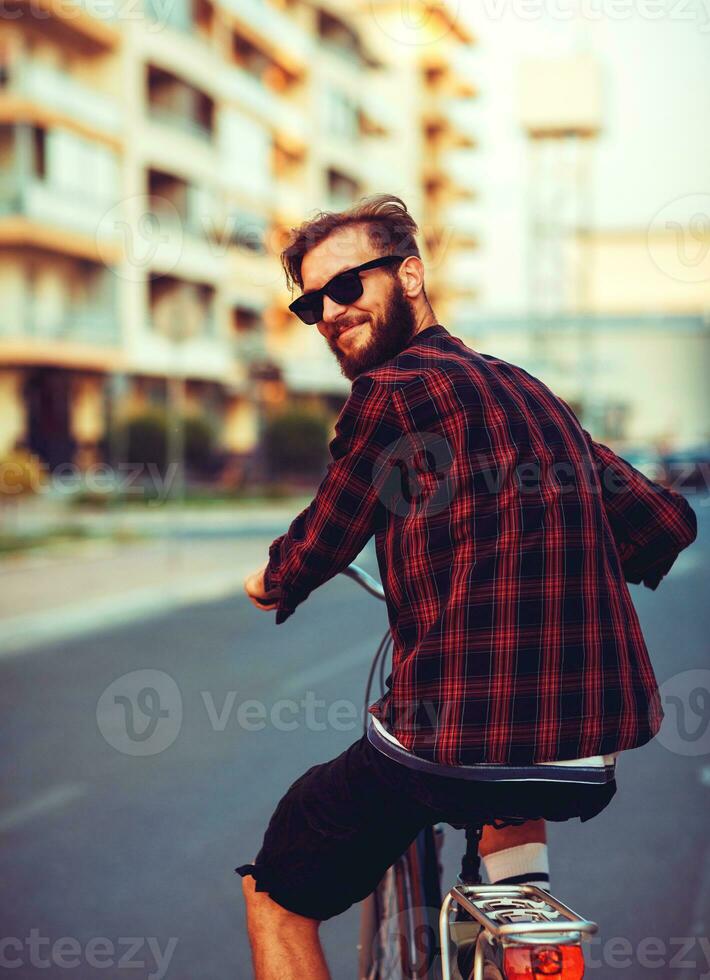 elegant Mens in zonnebril rijden een fiets Aan stad straat foto