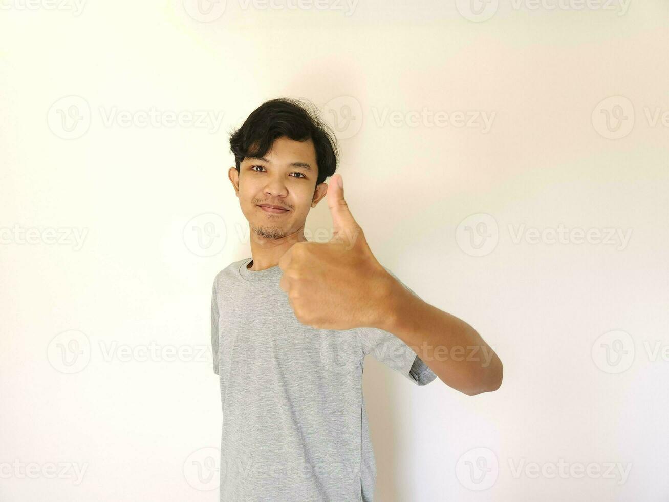 gelukkig Aziatisch Mens shows duim omhoog net zo een mooi zo hand- teken geïsoleerd Aan wit achtergrond foto
