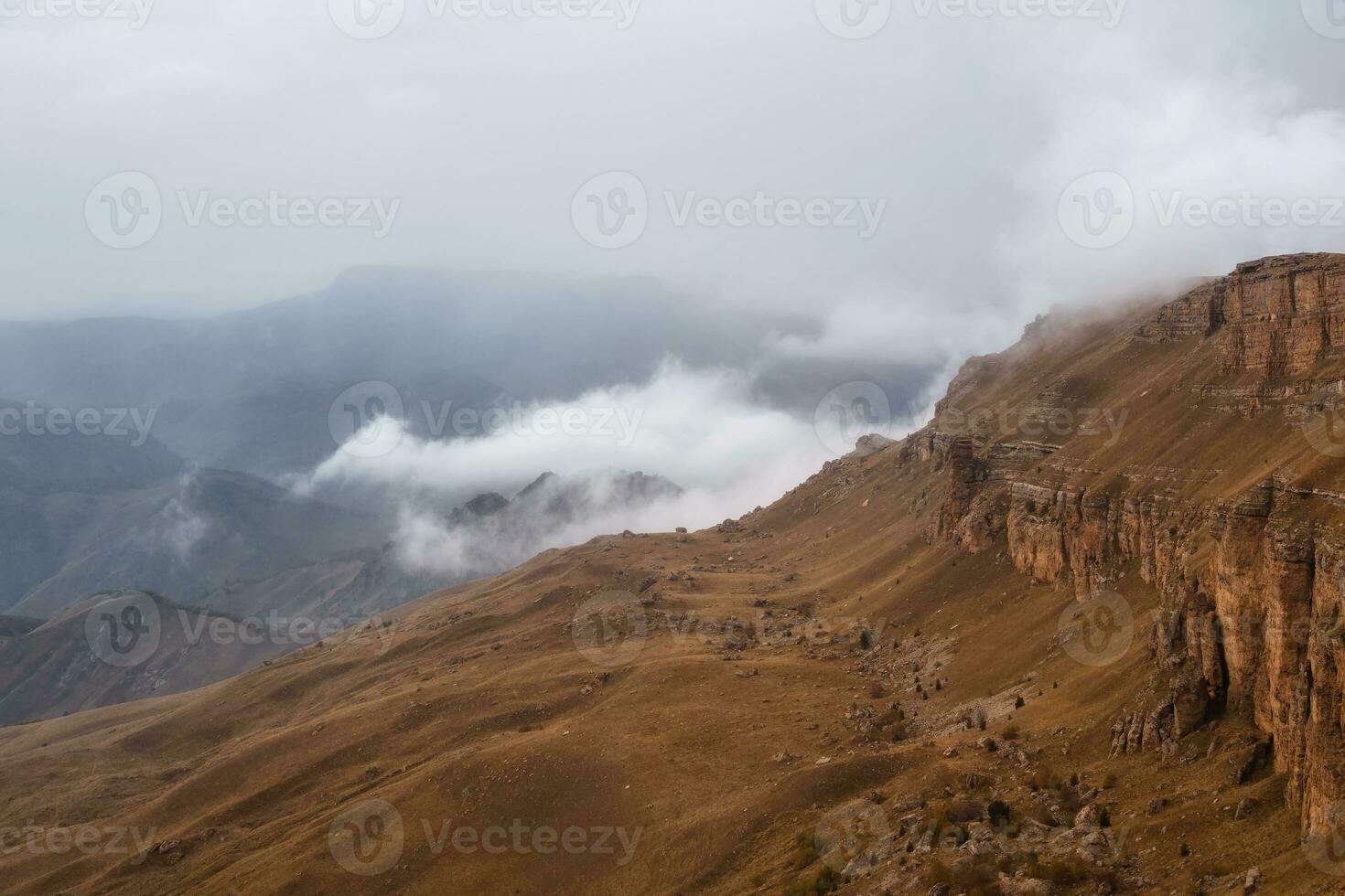 bermamyt plateau. mistig berg visie van klif Bij heel hoog hoogte. toneel- alpine landschap met mooi scherp rotsen in zonsopkomst. mooi landschap Aan afgrond rand met scherp stenen. foto