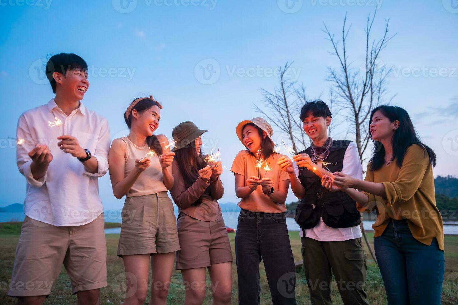 groep van jong Aziatisch mensen zijn genieten camping , spelen sterretje in natuurlijk camping Bij schemering foto