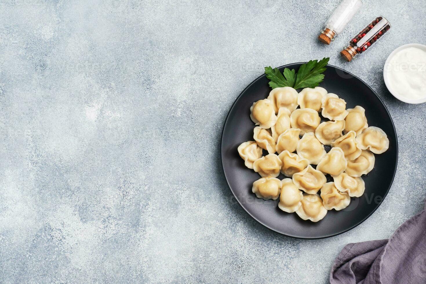 traditionele pelmeni, ravioli, knoedels gevuld met vlees op plaat, russische keuken. lichte betonnen achtergrond, kopieer ruimte. foto