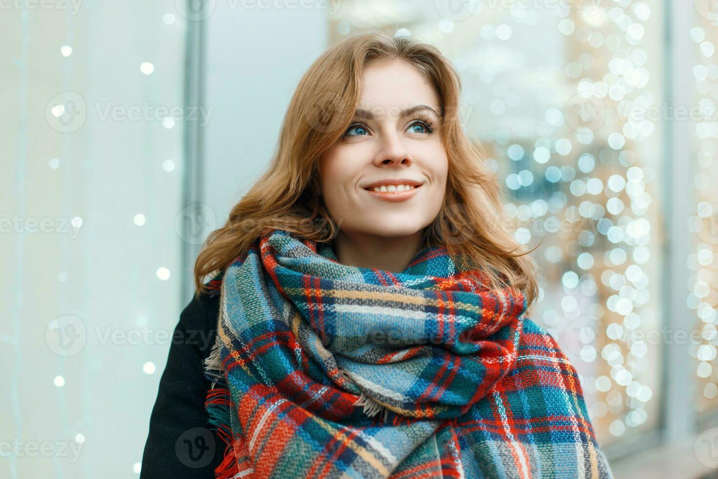 zoet vrouw met een glimlach in een mooi elegant sjaal Aan de achtergrond van lichten foto