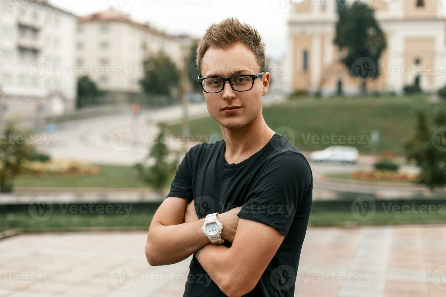 jong knap vent in zwart bril en een zwart t-shirt Aan de achtergrond van de stad foto