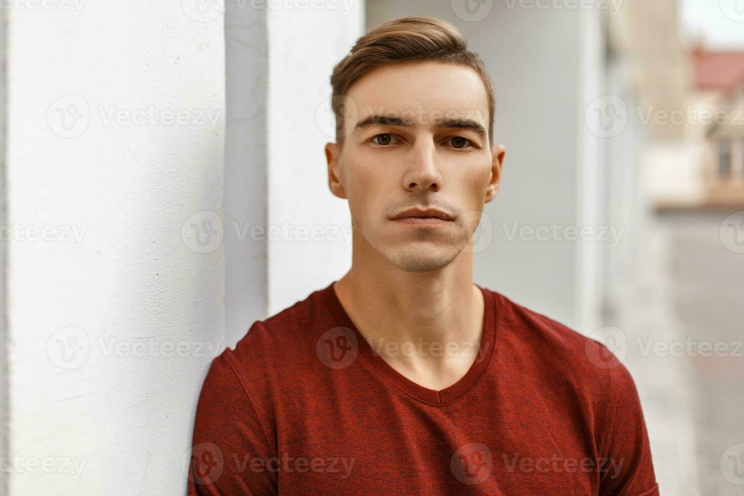 portret van een jong knap Mens met een kapsel in een hesje in de buurt een wit muur foto