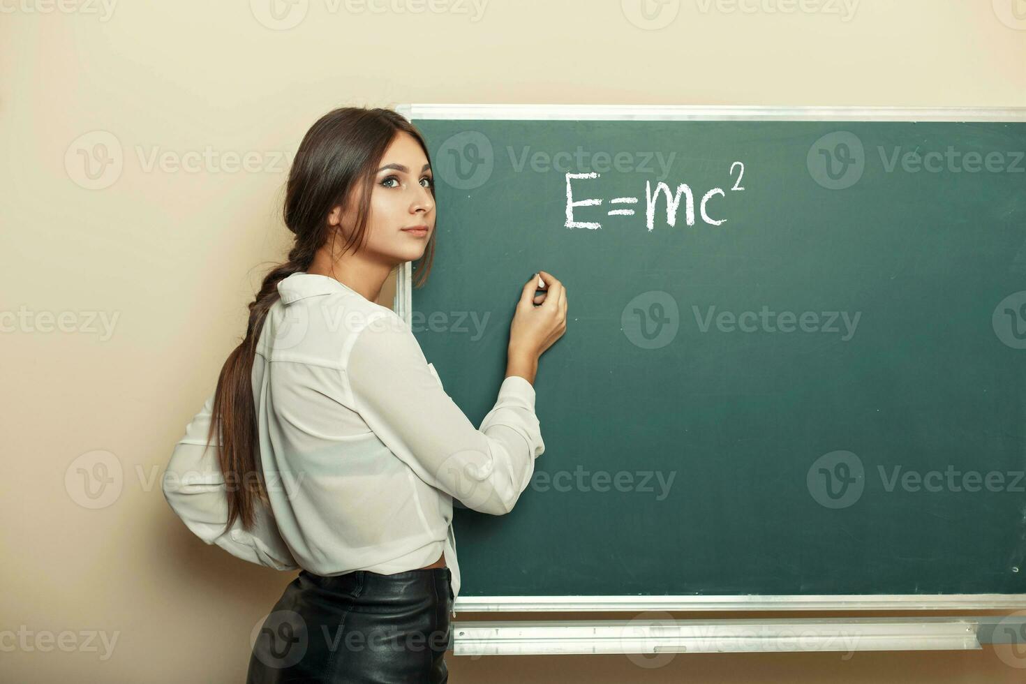 mooi jong meisje leraar schrijven formule Aan de schoolbord. foto