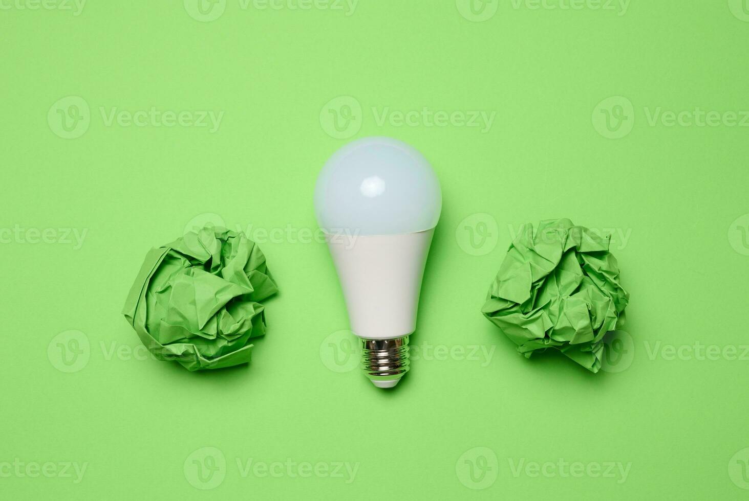 verfrommeld groen ballen van papier en glas wit lamp Aan groen achtergrond, top visie foto