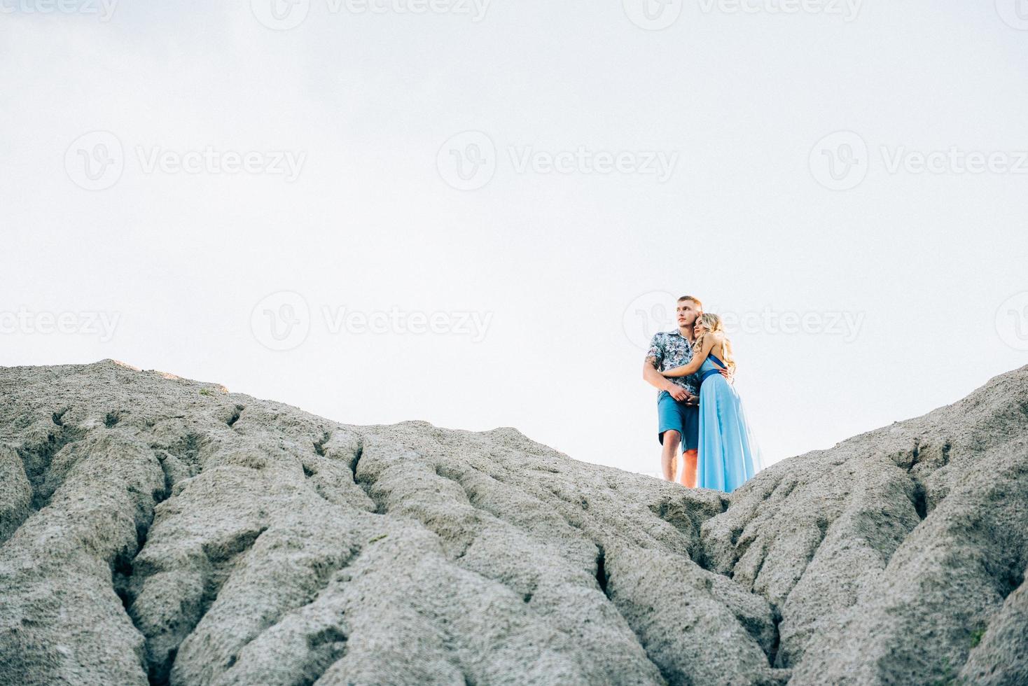 blond meisje in een lichtblauwe jurk en een man in een licht overhemd in een granietgroeve foto