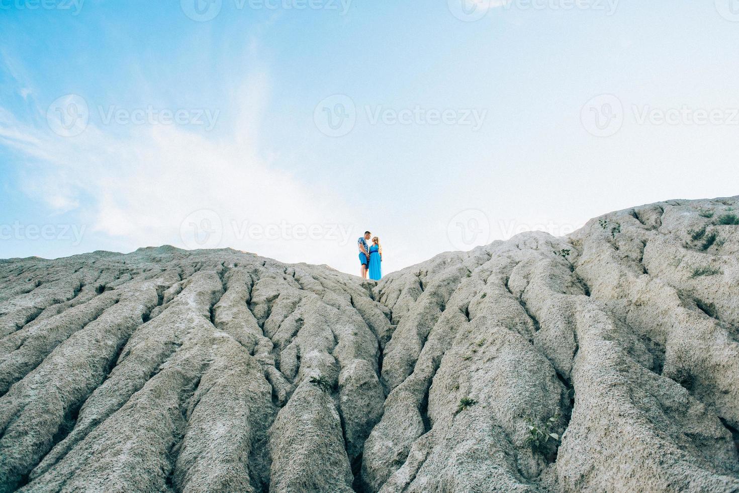 blond meisje in een lichtblauwe jurk en een man in een licht overhemd in een granietgroeve foto