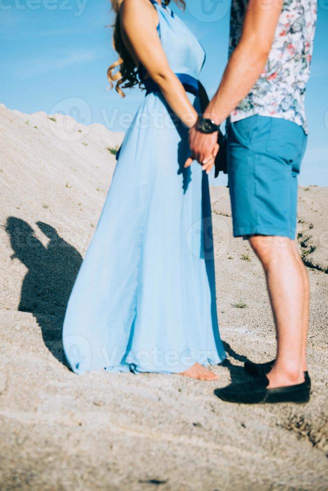 blond meisje in een lichtblauwe jurk en een man in een licht overhemd in een granietgroeve foto