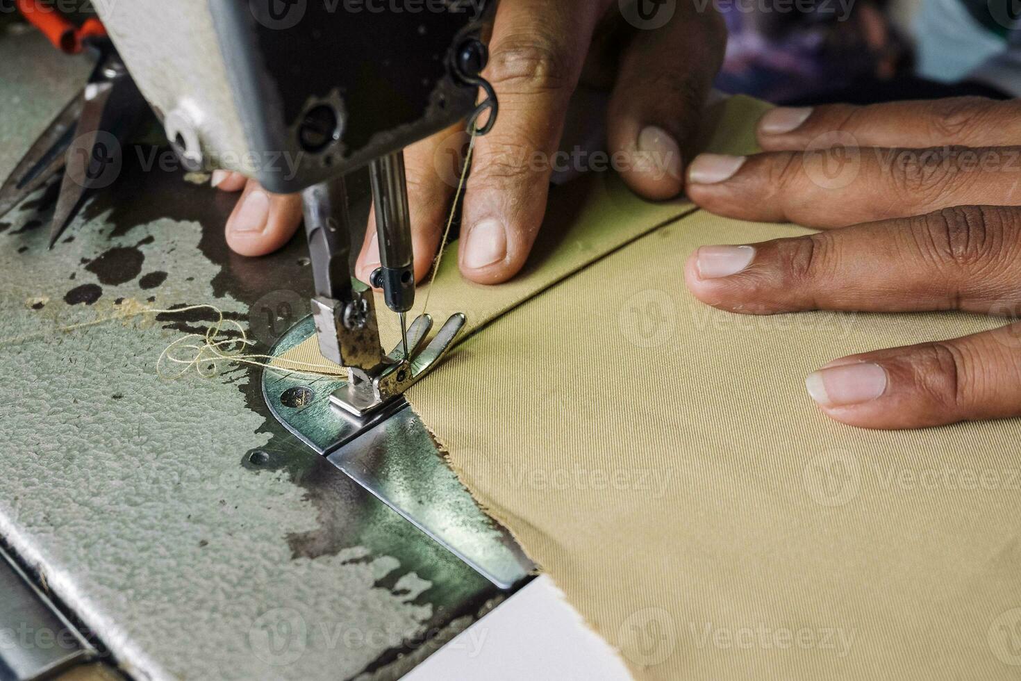 dichtbij omhoog visie van naaien werkwijze. handen stiksels kleding stof Aan professioneel fabricage machine Bij werkplaats foto