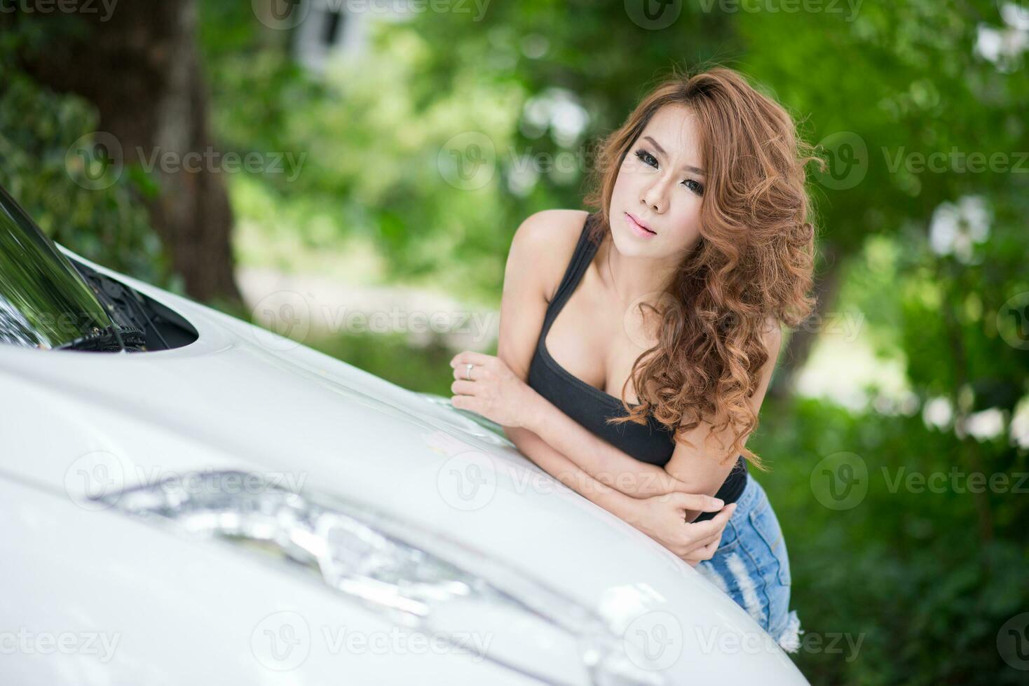 sexy meisje in zwart hesje is poseren Aan kap auto foto