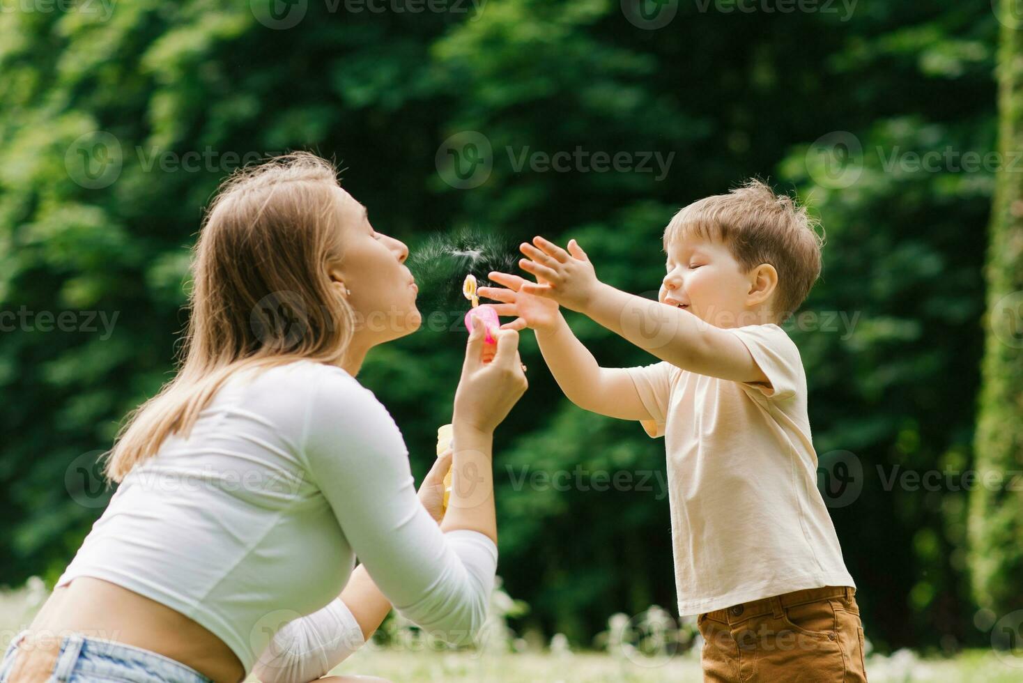 familie weekend van een moeder en haar weinig zoon. liefhebbend ouder hebben pret blazen zeep bubbels met een drie jaar oud jongen foto