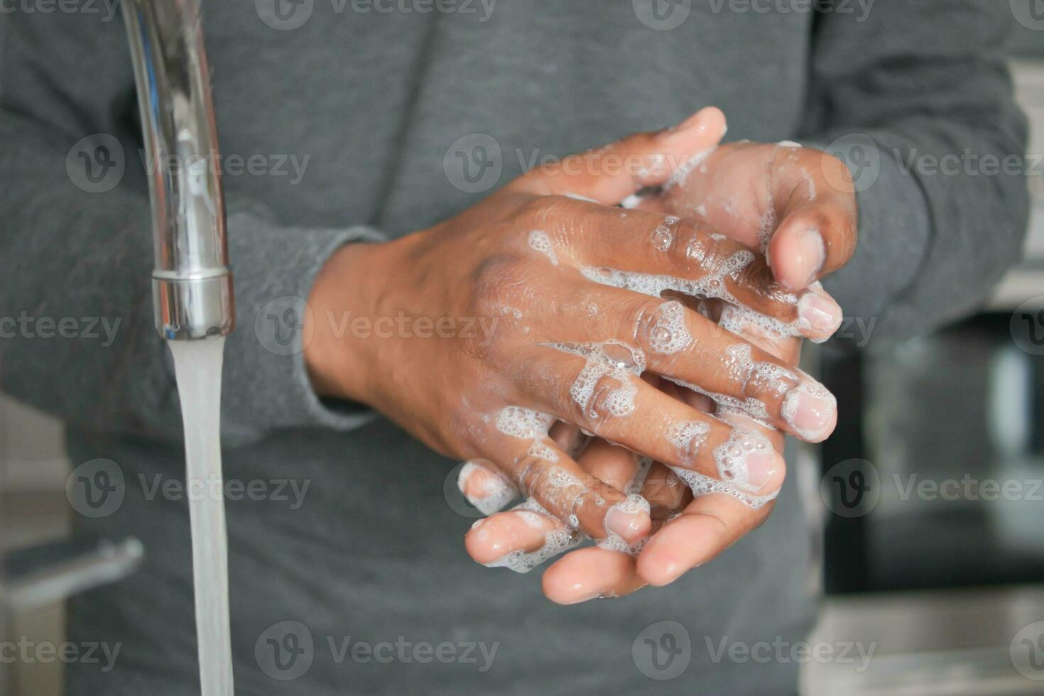 jonge man handen wassen met zeep warm water foto