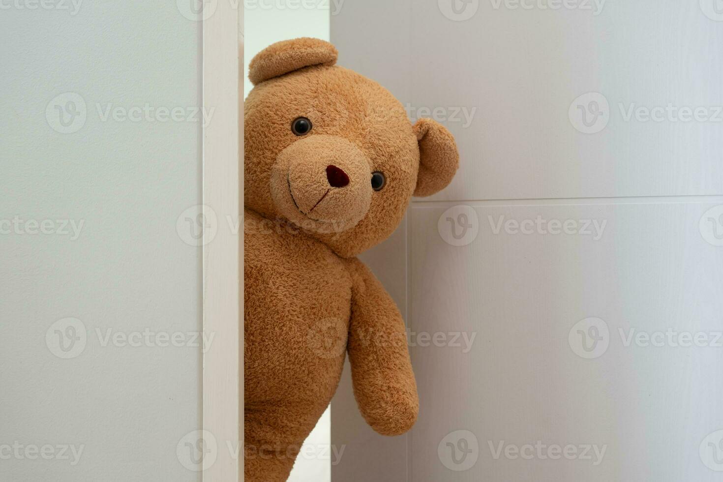 schattig bruin teddy beer speelgoed- sluipen achter de deur en verrassing naar feliciteren de speciaal dag vakantie feesten. spel kind, dag zorg, welkom, kind dag, verlegen jeugd, partij grappig, gevuld pop foto