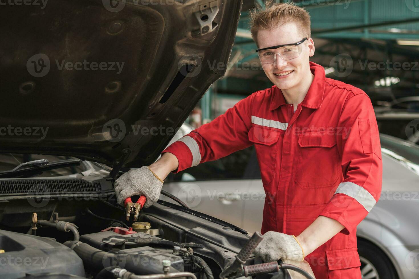 auto monteur werken in garage, technicus Mens werken in auto onderhoud, technici met opladen kabels voor auto accu, auto reparatie, en onderhoud foto