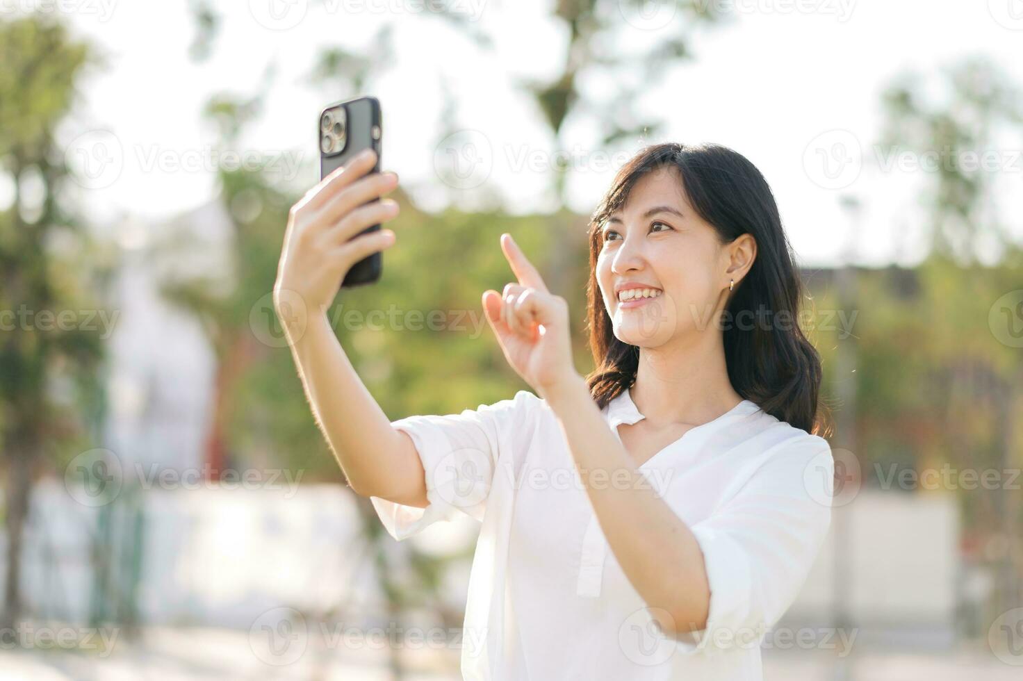 portret mooi jong Aziatisch vrouw met slim mobiel telefoon in de omgeving van buitenshuis natuur visie in een zonnig zomer dag foto
