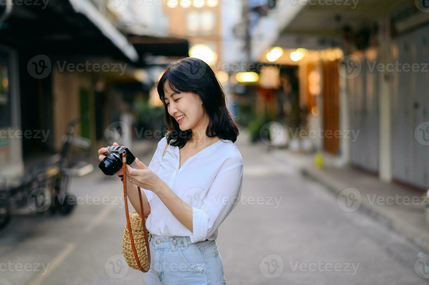 portret van Aziatisch vrouw reiziger gebruik makend van camera Bij straat van Bangkok, Thailand. Azië zomer toerisme vakantie concept foto