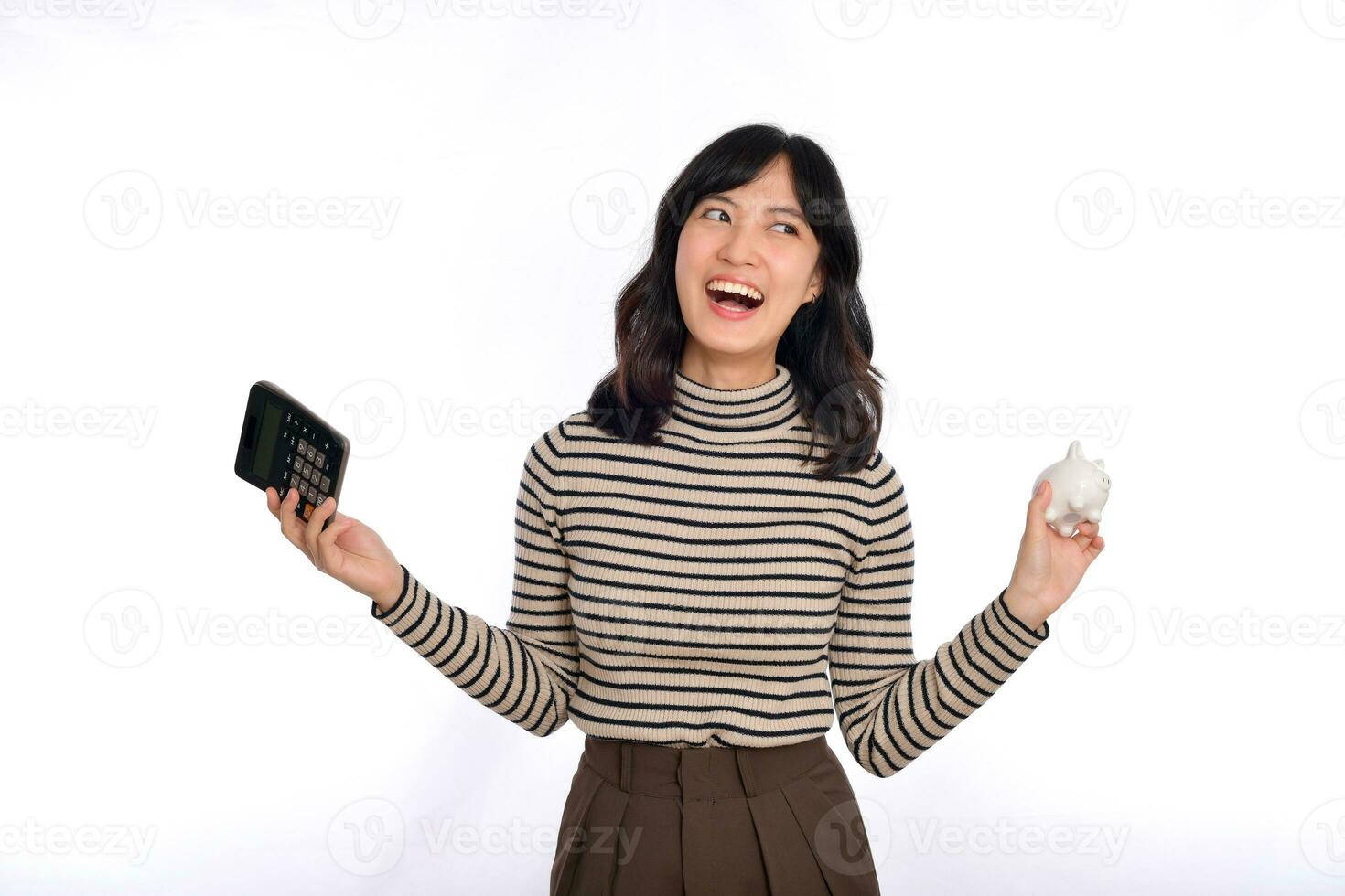 portret van jong Aziatisch vrouw gewoontjes uniform Holding wit varkentje bank en rekenmachine geïsoleerd Aan wit achtergrond, financieel en bank besparing geld concept foto