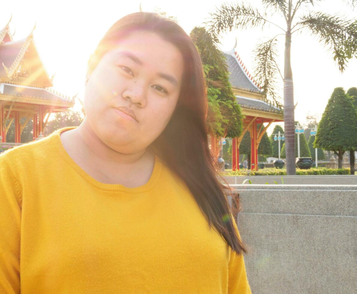 portret van een dik Aziatisch vrouw met lang zwart haar- vervelend een geel blouse met lang mouwen. staand en op zoek toekomst met krachtig ogen, een glimlach dat is vastbesloten en echt. vol verbeelding. foto