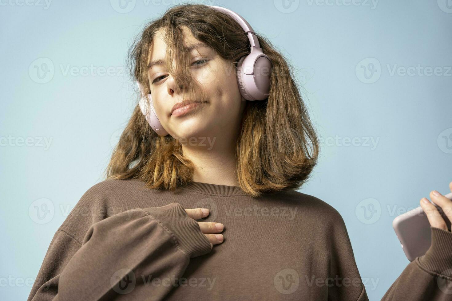 een schattig Europese tiener- meisje luistert naar muziek- in draadloze hoofdtelefoons van een smartphone foto