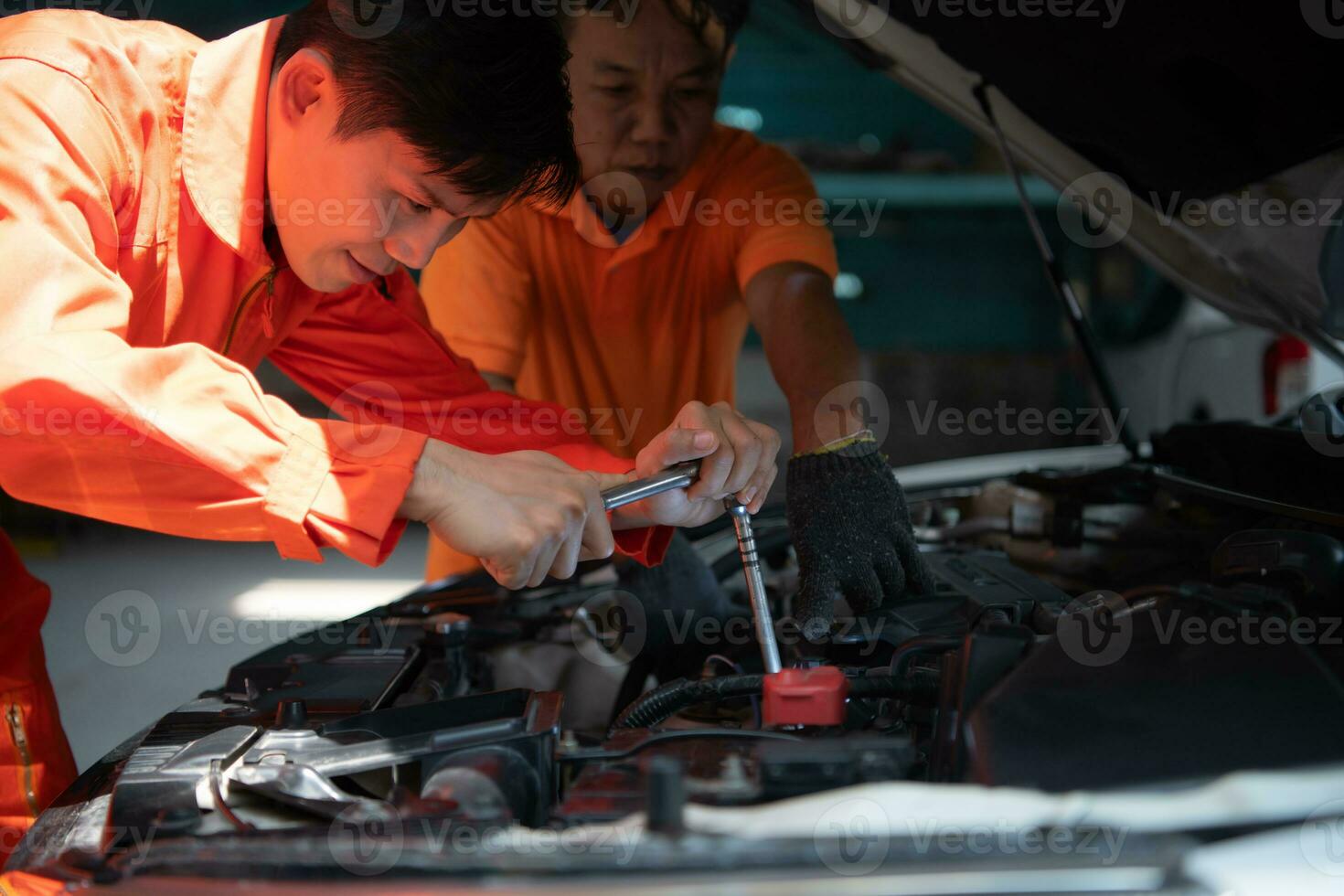 beide van auto mechanica zijn inspecteren de motor van een klanten auto wezen gebracht in voor reparatie Bij een garage. foto