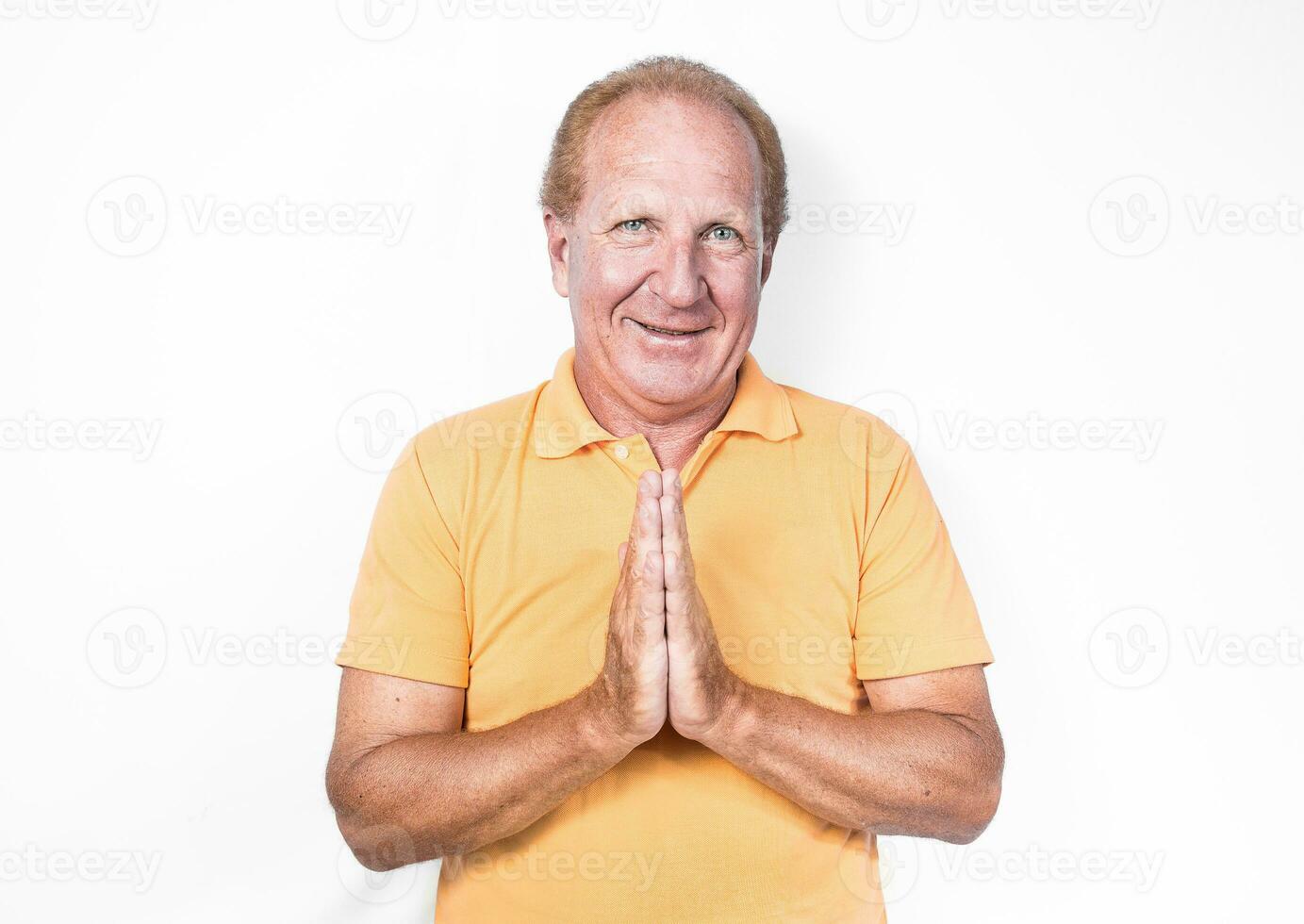 knap oud Mens in oranje poloshirt aan het doen Thais gebaar of bedelen foto