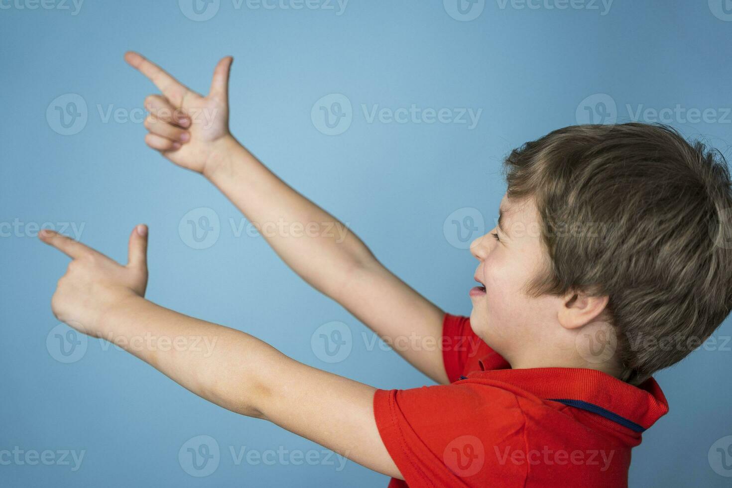 jongen vrolijk schiet zijn vingers gevouwen in de vorm van een pistool. de jongen zetten zijn vingers in de vorm van een geweer foto