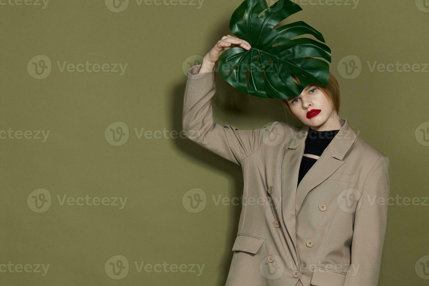 portret van een vrouw in jas rood lippen mode palm blad geïsoleerd achtergrond foto