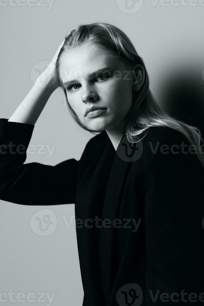 esthetisch nadenkend verdrietig blond jong model- poseren in klassiek jasje aanraken kous haar- Bij studio. mooi dame attent op zoek en strelen haar krullen. zwart en wit concept foto