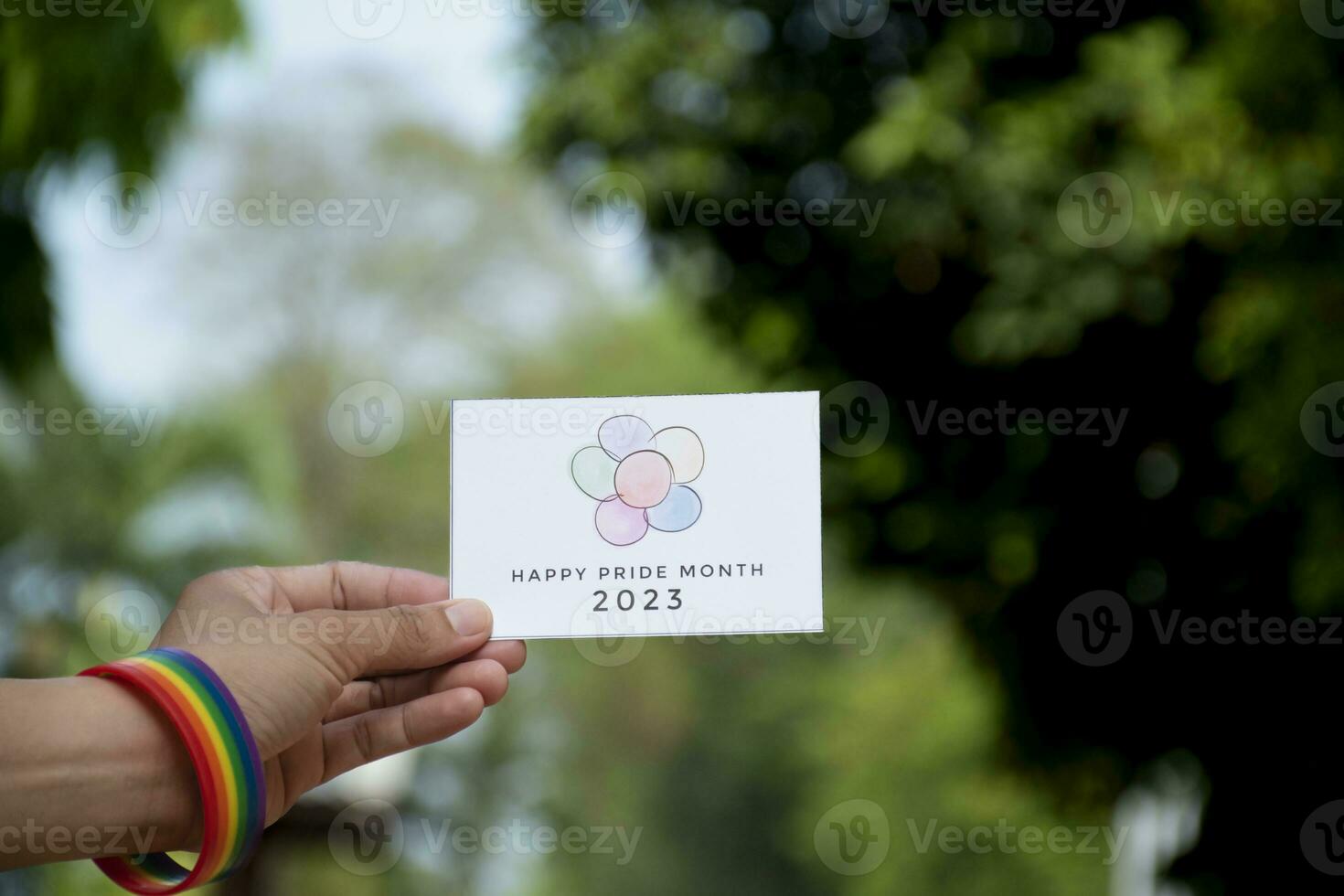 'Vrolijk trots maand 2023' kaart Holding in hand- welke heeft regenboog polsbandje in de omgeving van het, concept voor uitnodigend allemaal mensen naar toetreden de lgbtq evenementen in de omgeving van de wereld in trots maand. foto