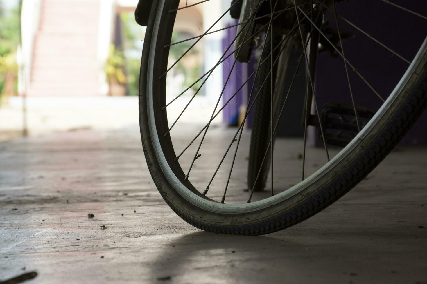 detailopname visie van wijnoogst fiets welke heeft vlak wielen en geparkeerd Aan cement verdieping van beneden van de gebouw, zacht focus. foto