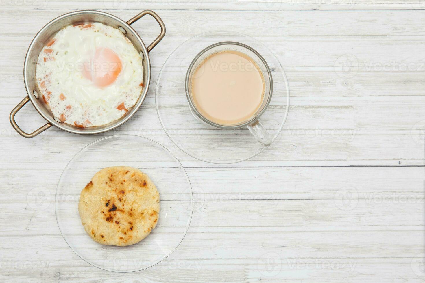 gebakken ei, koffie en arepa Aan houten wit tafel foto