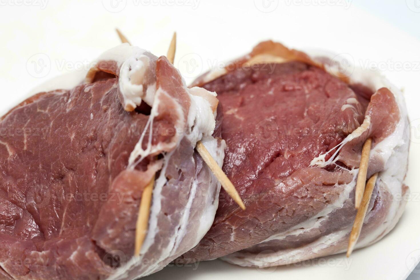 rauw rundvlees lende medaillon verpakt in varkensvlees spek. filet mignon voorbereiding. foto