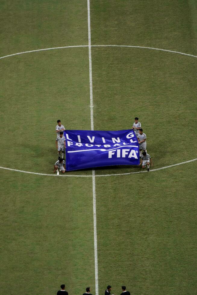 voetbal scheidsrechter in grijs overhemd Aan veld- Holding vlag met tekst leven Amerikaans voetbal. Jakarta, Indonesië, augustus 1, 2022 foto