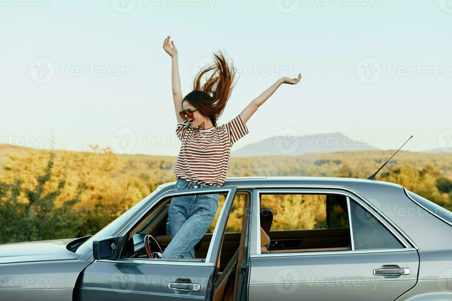 gelukkig vrouw reiziger beklommen Aan de auto en verspreiding haar armen glimlachen gelukkig. looks Bij de natuur in de omgeving van. levensstijl in reizen en vreugde foto