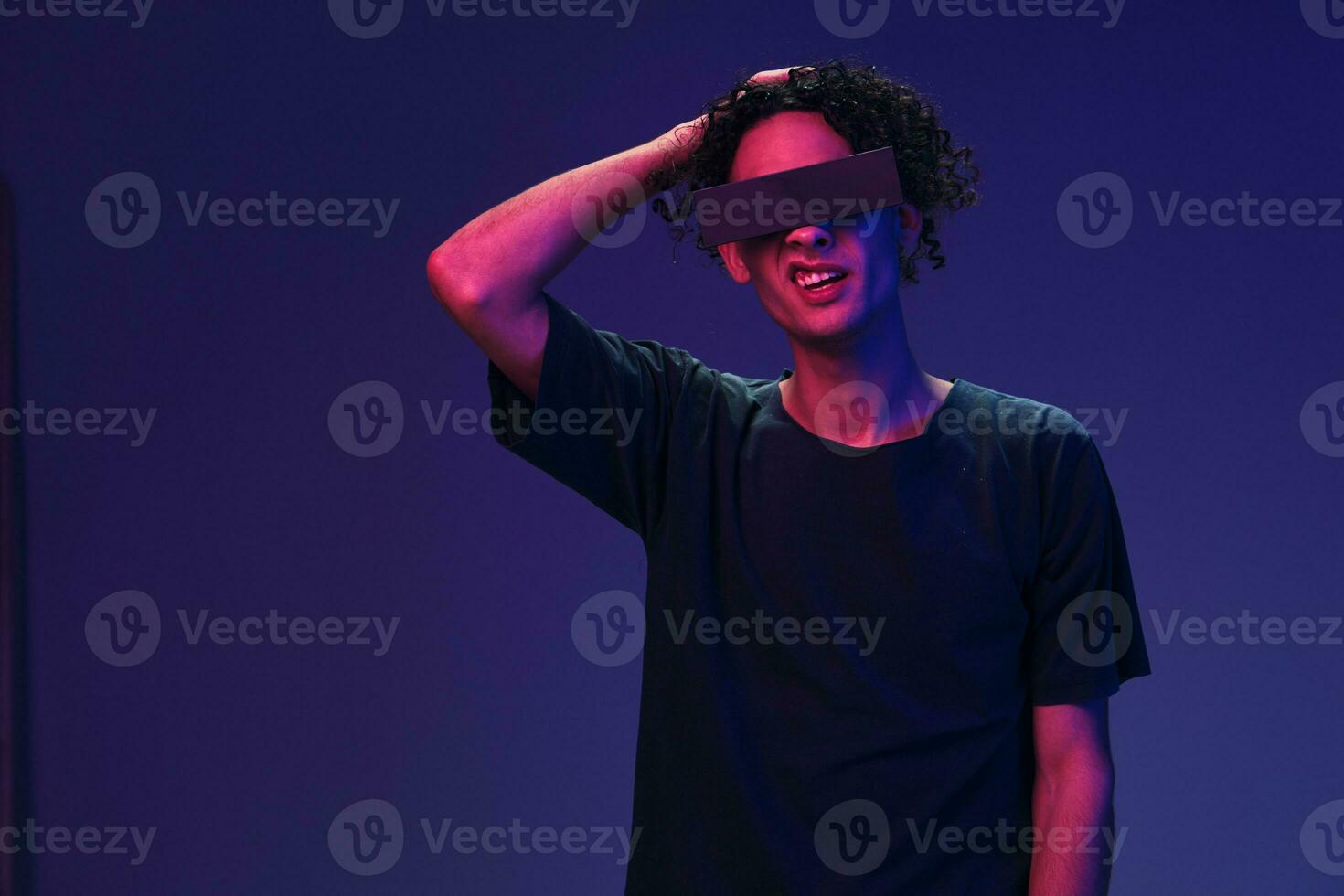 geschokt verward elegant gebruind gekruld Mens in zwart t-shirt modieus eyewear poseren geïsoleerd Aan kleur roze blauw achtergrond. koel mode bieden. virtueel realiteit nieuw verzameling concept. kopiëren ruimte voor advertentie foto